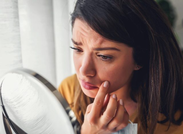 woman concerned look on face looking in mirror skin cancer