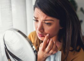 woman concerned look on face looking in mirror skin cancer