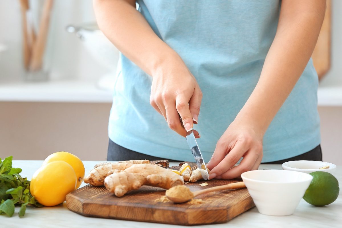 woman cutting ginger on cutting board