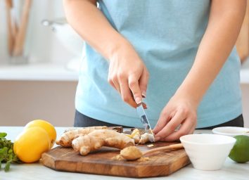 woman cutting ginger on cutting board