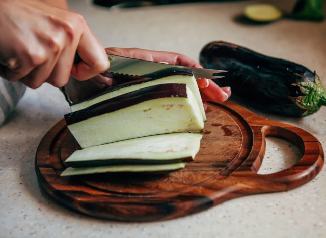 woman cutting raw eggplant