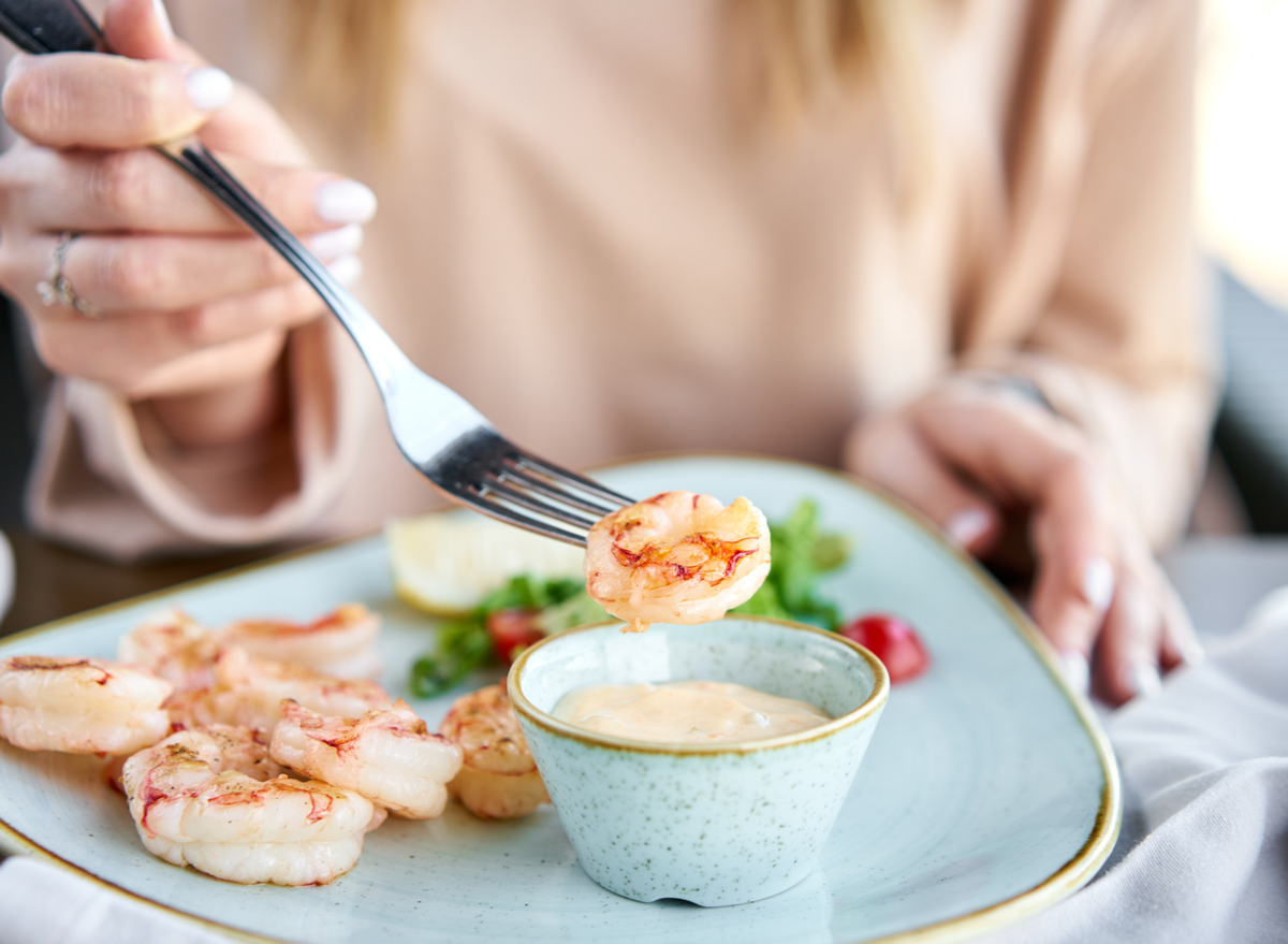 woman dipping shrimp into sauce