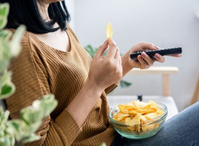 woman eating potato chips while watching tv