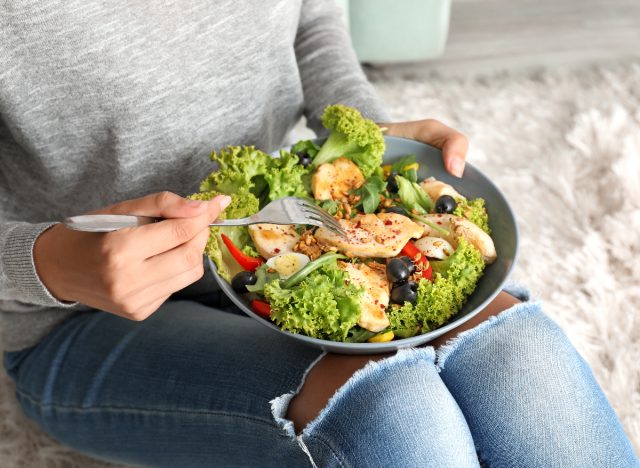 woman eating chicken and salad
