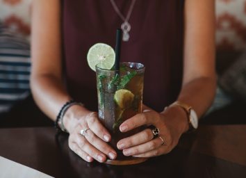 woman holding glass of iced tea with lime and mint