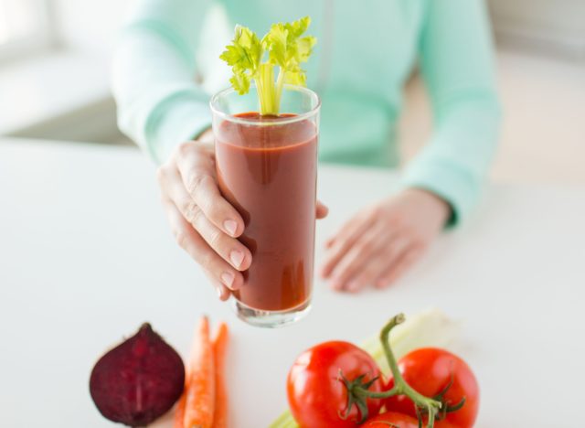 woman holding glass of tomato juice