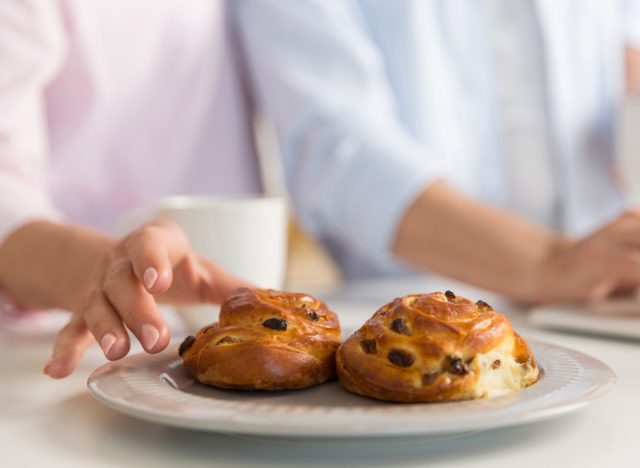 woman taking pastry from plate