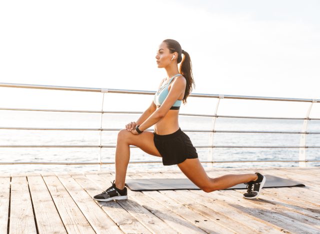 woman doing walking lunges on boardwalk