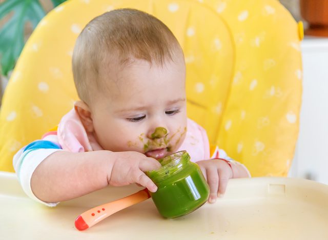 Baby eating green baby food