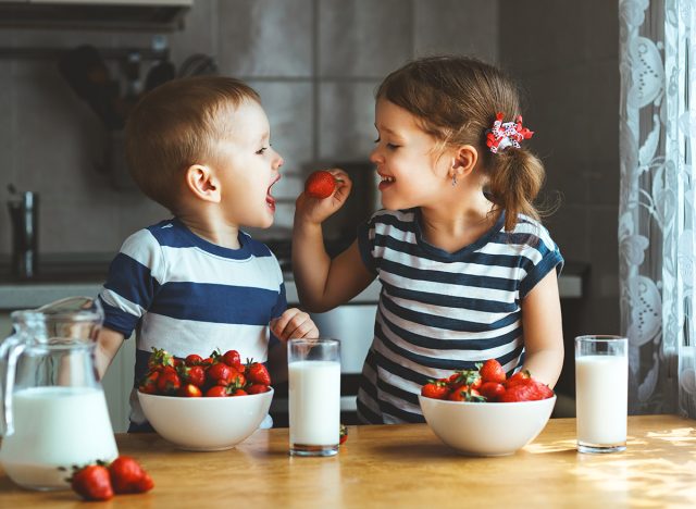 Kids eating strawberries and drinking milk