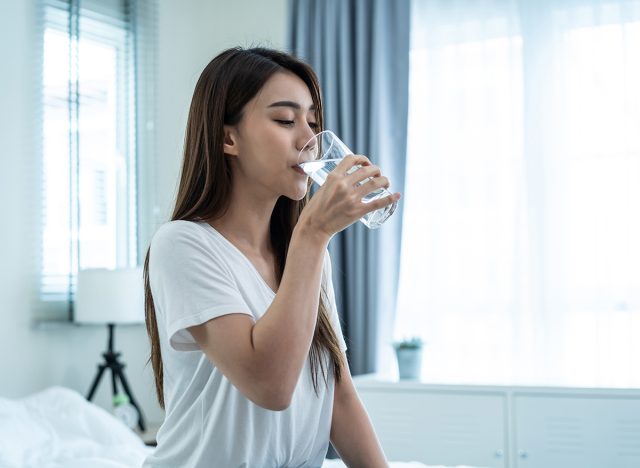 Woman drinking water out of bed