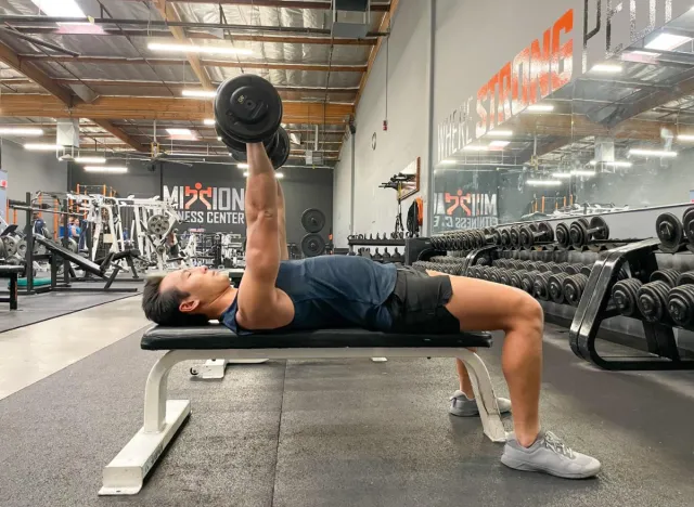 trainer performing dumbbell bench press exercise to lead an incredibly healthy lifestyle