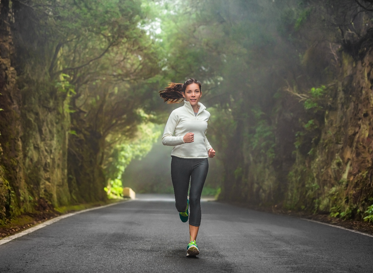 female running down tree-lined road, demonstrating the best diet for long-distance runners