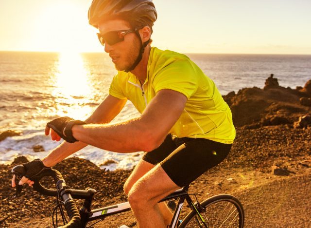 fitter mann, der fahrrad am wasser entlang fährt, sonnenuntergang