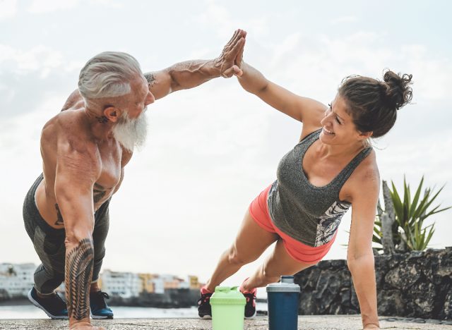 fit, mature couple planks and high-fives