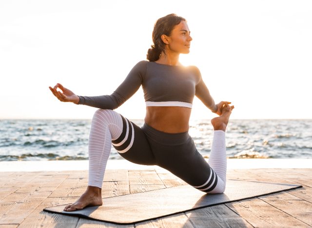 fit woman doing yoga by the beach