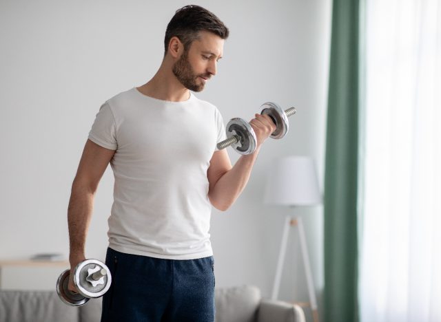 man in his 40s holding dumbbells, demonstrating fitness mistakes at 40