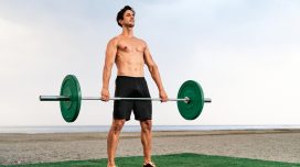 man performing barbell exercise on turf by the beach to lose belly fat and slow aging