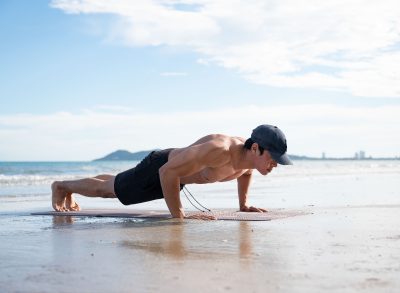 fit man performing beach pushups, demonstrating how to start to lose belly fat in seven days