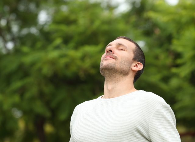 man doing facial exercise outdoors