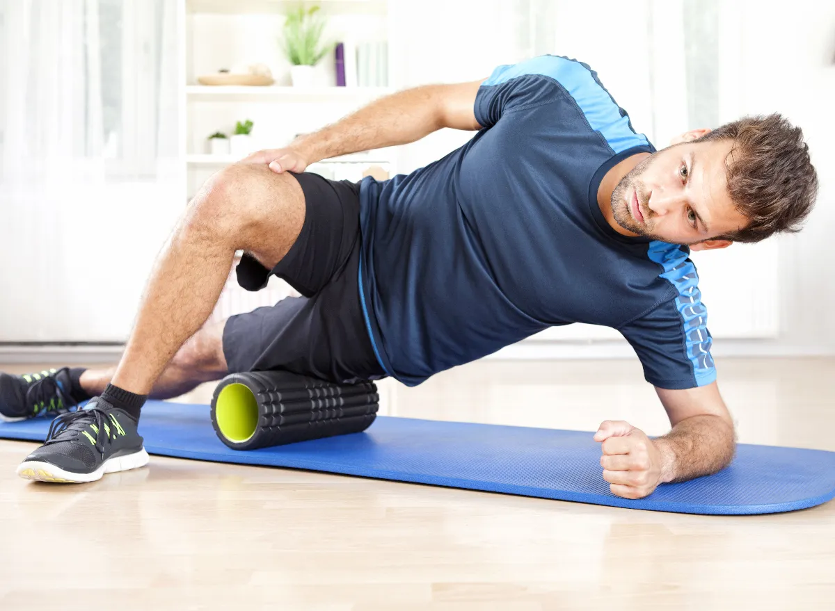 man performing foam rolling exercises for knee pain at home