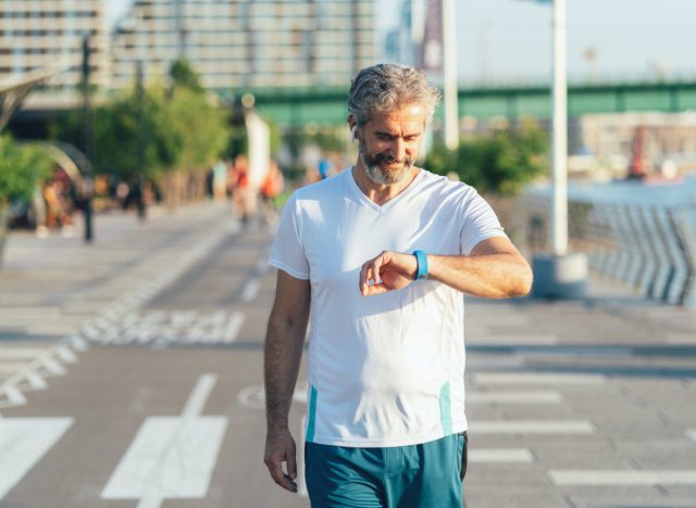 man checking watch, demonstrating cardio tricks for burning more calories while walking