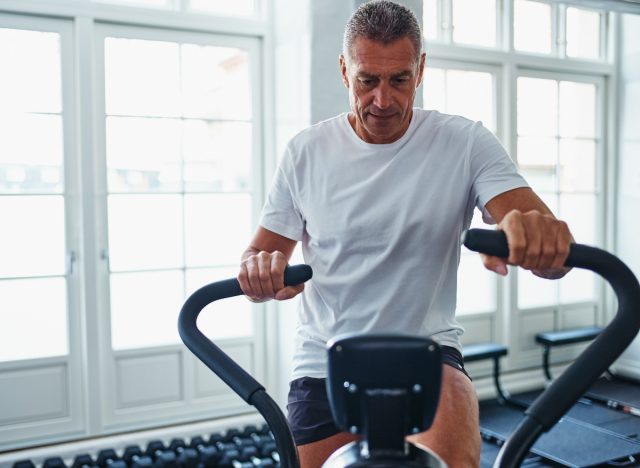 mature man doing HIIT workout to slow aging on exercise bike