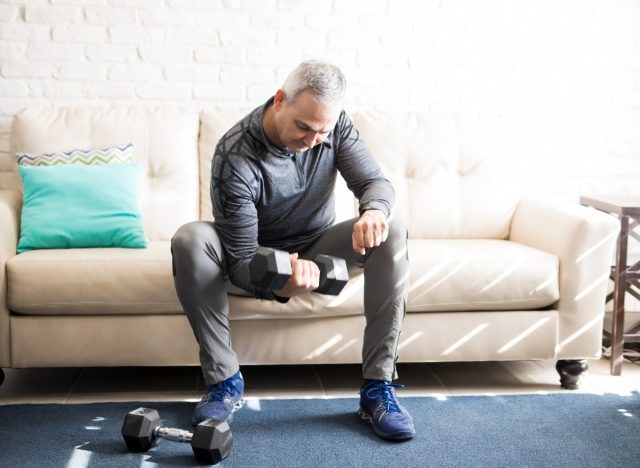 mature man lifting dumbbells at home demonstrating the question, are shorter workouts more effective