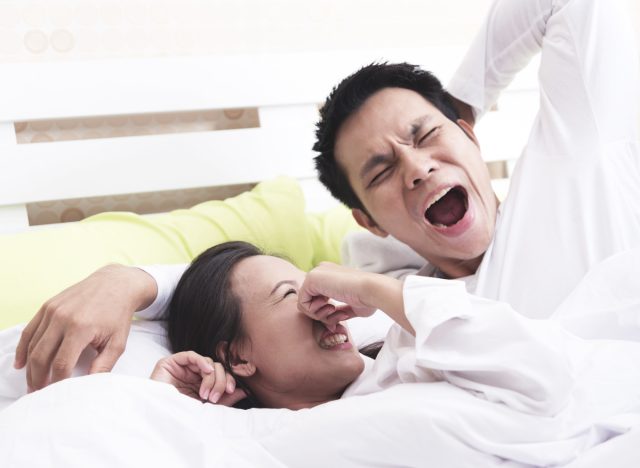 woman smelling partner's bad breath in bed, get rid of morning breath fast