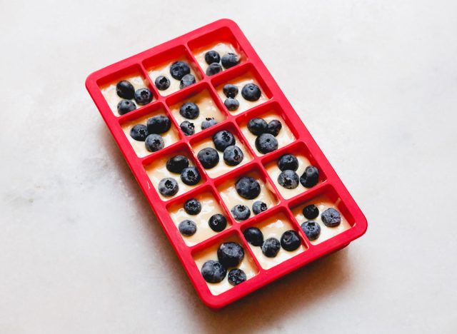 pancake batter in a silicone ice cube tray with blueberries