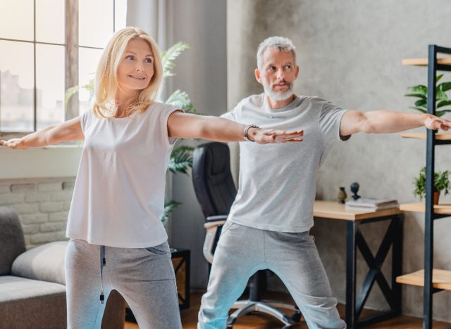 senior couple doing yoga, demonstrating strength training habits that slow aging