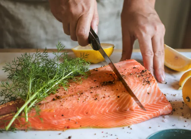 People slicing fresh salmon with dill and lemon, food to speed up weight loss