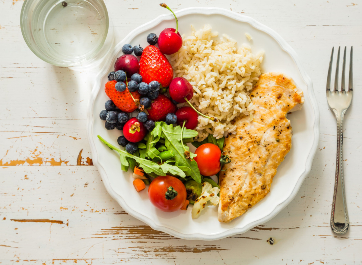 portioned plate with chicken, rice, fruit, and salad
