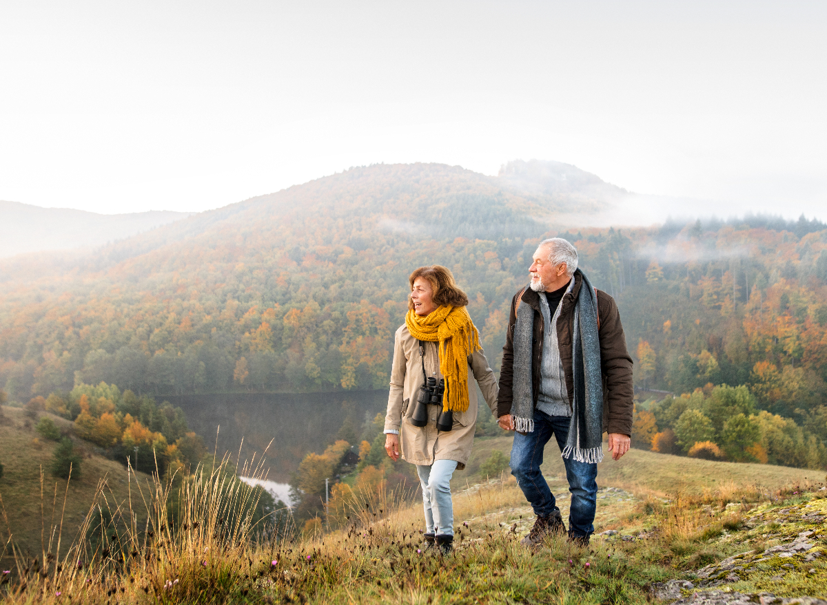 senior couple demonstrating the hiking habits to slow aging while on a fall hike