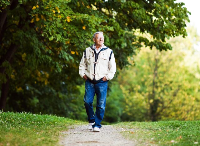 senior man strolls through park, getting in exercise to become a centenarian
