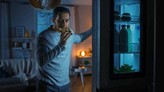 man-in-kitchen-eating-late-at-fridge
