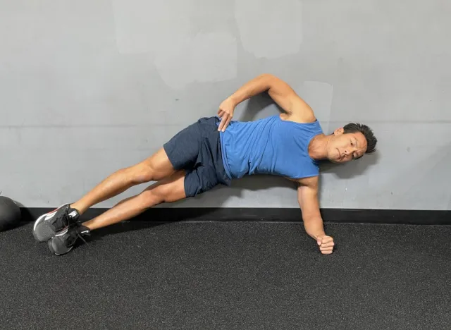 trainer demonstrating side plank hip raise to get a flatter stomach at 50