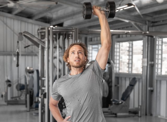man performing single-arm press to lose top layer of belly fat