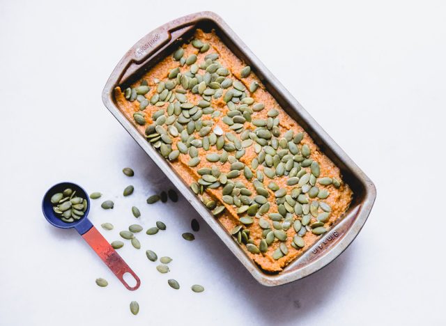 topping the pumpkin loaf batter with pepitas before baking