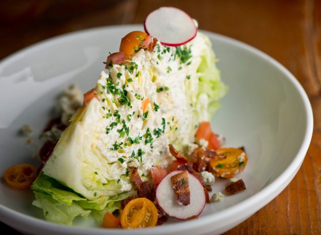 wedge salad with iceberg lettuce, blue cheese dressing, bacon, and tomatoes