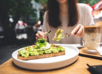 woman cutting avocado toast at outdoor resturant