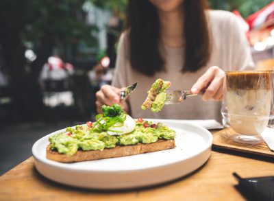 woman cutting avocado toast at outdoor resturant