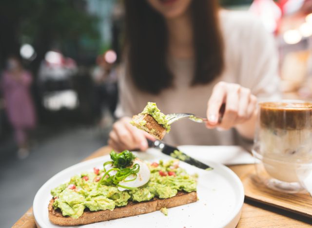 woman cutting avocado toast at outdoor resturant