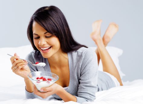 woman eating yogurt with raspberries