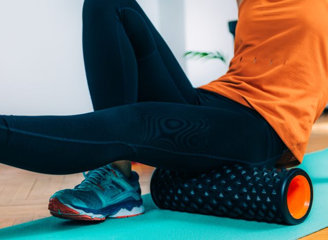 woman using a foam roller on her thighs for lower back pain