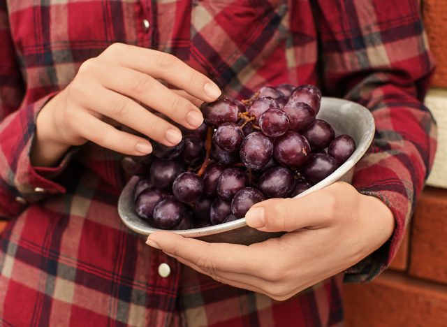 woman holding bowl of red grapes