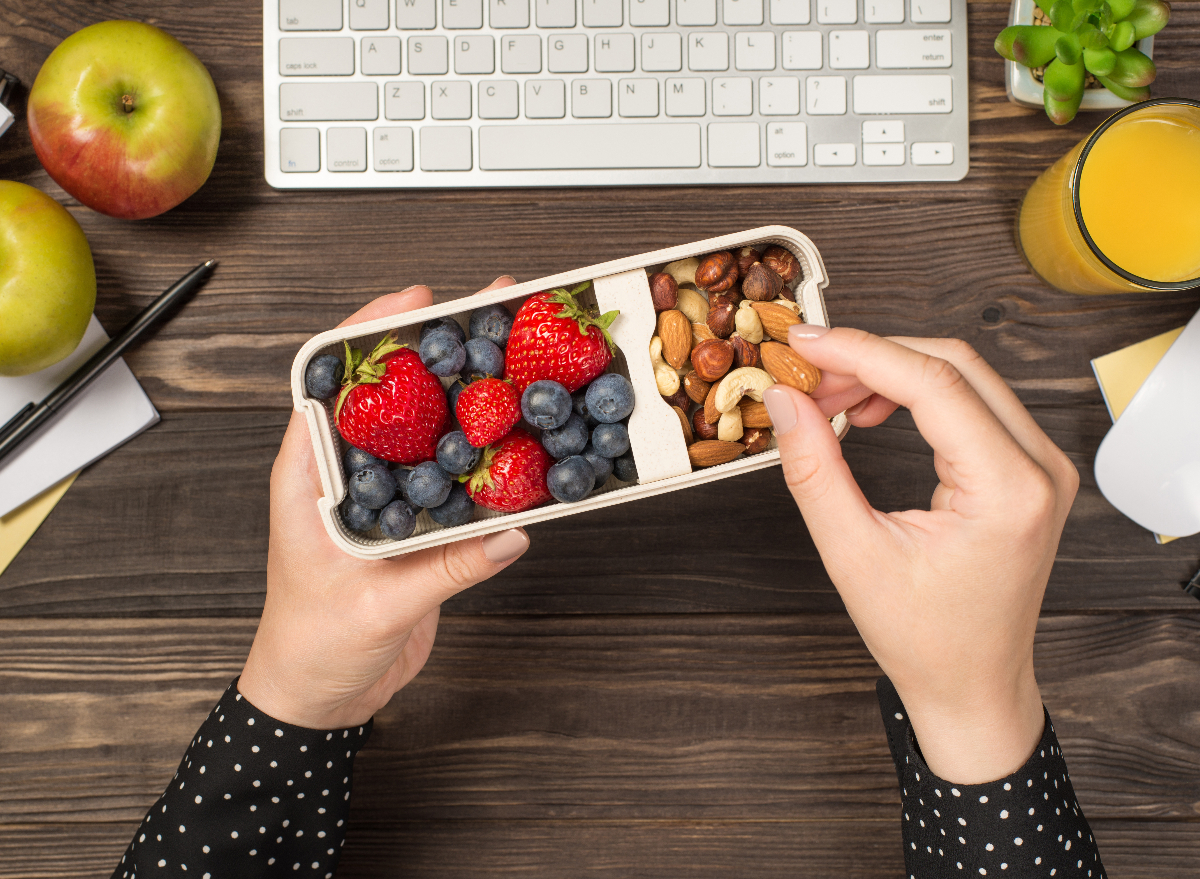 woman holding lunchbox with blueberries, strawberries, and nuts