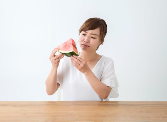 Woman holding and looking at watermelon