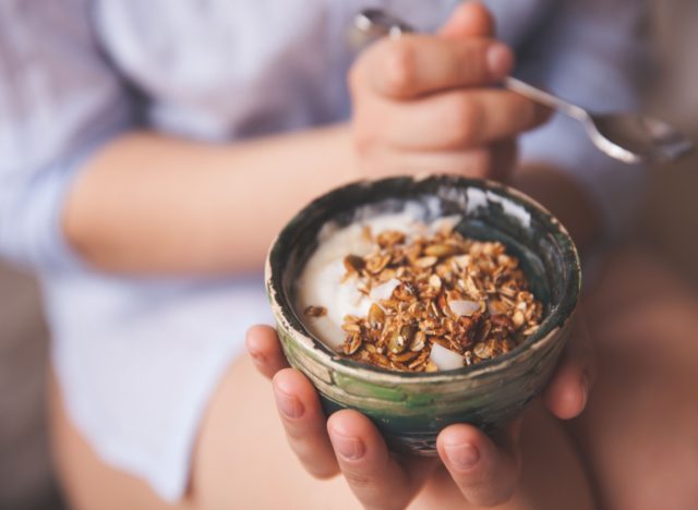 woman holding yogurt with granola