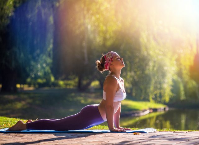woman doing outdoor yoga flow by lake